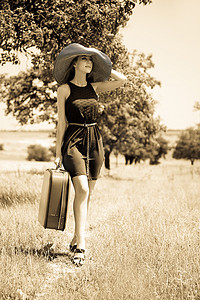 带着手提箱的孤独的女孩在乡下