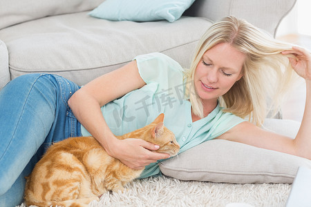 沙发猫摄影照片_女人在地毯上玩头发时抚摸着猫