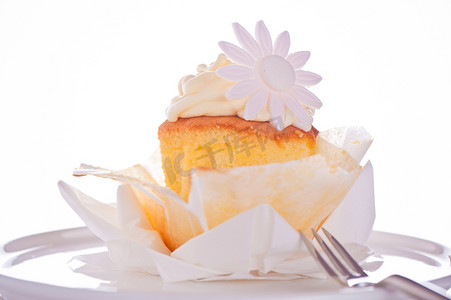 白色背景上带有香草奶油和糖花的纸杯蛋糕