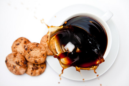 咖啡液体飞溅摄影照片_糖滴在一杯咖啡和饼干中