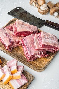 牛骨头摄影照片_白石背景上的生小牛小牛短肋肉，配料和旧屠刀