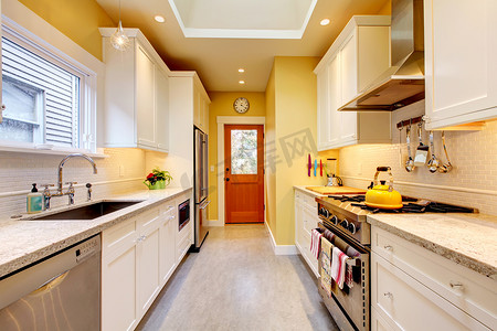 白色的现代厨房摄影照片_黄色和白色狭窄的现代厨房。
