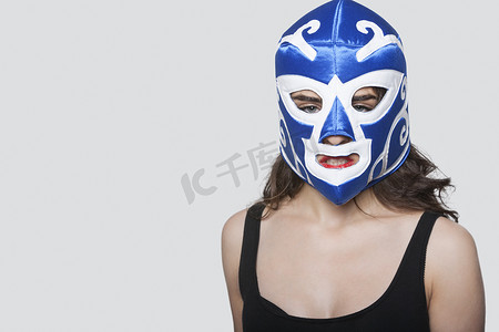灰色背景下戴着摔跤面具的年轻女子的画像