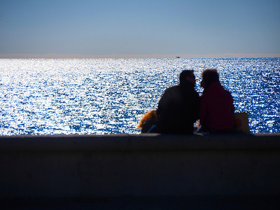从坐在海边的后面看到无法辨认的拥抱恋人的模糊图像