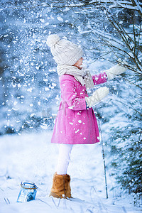 玩雪摄影照片_可爱的小女孩在圣诞节的冬天在户外的森林里玩雪