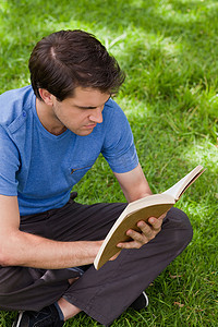 年轻严肃的男人盘腿坐着看书