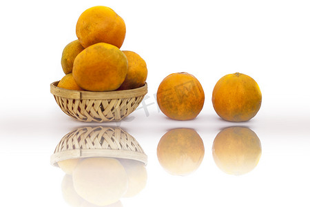 果篮上摄影照片_装满未加工的有机新鲜橙子的水果篮与反射一起在白色上被隔离。