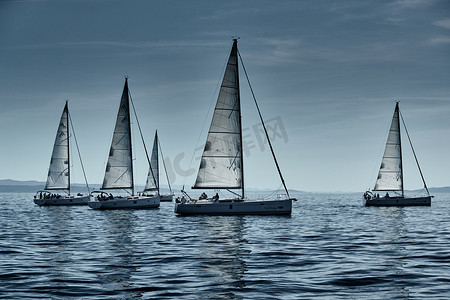 克罗地亚，亚得里亚海，2019 年 9 月 15 日：背景是帆船比赛、帆船赛、水上帆的倒影、激烈的竞争、鲜艳的色彩、带风车的岛屿