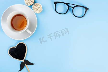 父亲节快乐背景概念，带眼镜、一杯茶和蓝色背景上的黑色心形，带有文本复制空间。