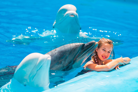 在海豚馆与海豚一起游泳的快乐小女孩