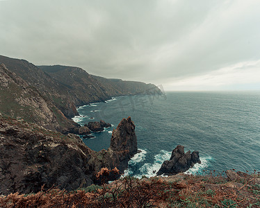 欧洲悬崖和巨石的景观照片，野生海洋以绿色和棕色的色调与它相映成趣