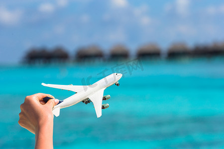 小飞机旅游摄影照片_在热带海滩背景水上平房的小白色玩具飞机