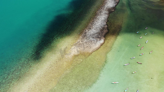 彩色的珊瑚摄影照片_小彩色木制渔船，漂浮在蔚蓝的海水表面，越过海洋海岸的珊瑚。