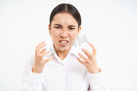 愤怒的办公室女士，亚洲女商人因愤怒而尖叫和握紧拳头，因沮丧而颤抖，站在白色背景上，发脾气