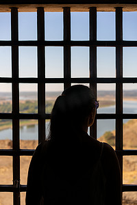 朱家角剪影摄影照片_葡萄牙阿连特茹风景中带网格窗的 Juromenha 城堡剪影的女性