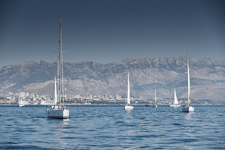 克罗地亚，亚得里亚海，2019 年 9 月 15 日：背景是帆船比赛、帆船赛、水上帆的倒影、激烈的竞争、鲜艳的色彩、带风车的岛屿