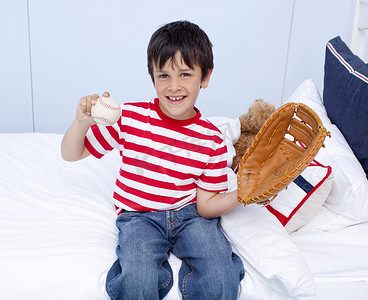 打游戏人摄影照片_快乐的小男孩在床上打棒球