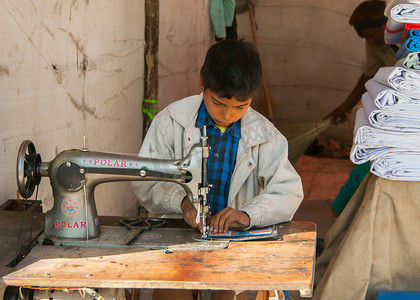 童工，男孩在市场上的摊位缝纫。