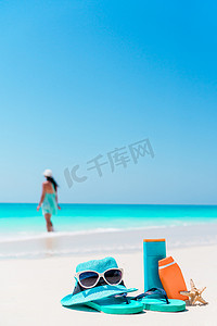 沙滩背景摄影照片_白色沙滩背景海洋上的防晒霜瓶、护目镜、海星和太阳镜
