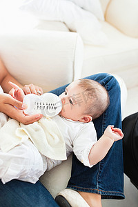 一位母亲给坐在沙发上的婴儿喂奶的特写镜头
