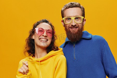 广告黄色摄影照片_一对男女欢快地微笑着，戴着眼镜，在黄色背景、符号标志和手势、家庭拍摄、新婚夫妇中歪着头。