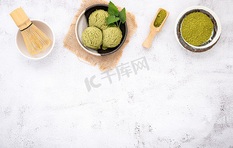 抹茶绿茶冰淇淋配华夫饼锥和薄荷叶设置在白色石头背景上。