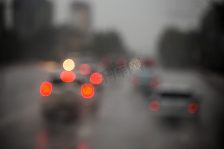 雨后夜间街道汽车交通的散焦图片-从道路看。