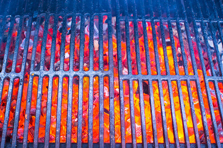 黑背景红光摄影照片_带热红光煤的空黑铸铁烤架