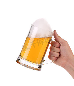 手拿啤酒摄影照片_手拿着一杯带泡沫的啤酒。