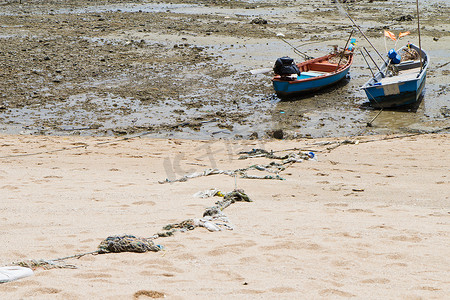 卡通打渔摄影照片_绳子绑在海滩上的一艘渔船上。