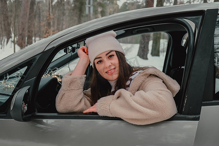 窗外下雪摄影照片_迷人的年轻女性看着车窗外等待旅行和微笑。