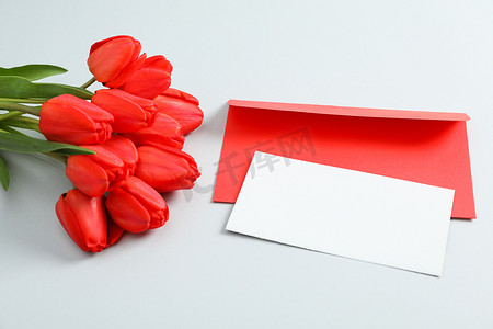 浅灰色背景上带有文字空间和美丽红色郁金香的信封，特写