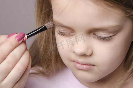 儿童脸上摄影照片_化妆师在女孩的脸上画眼皮