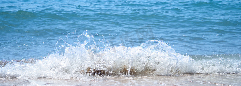 浅蓝色水花摄影照片_清澈的浅蓝色海水飞溅到海滩