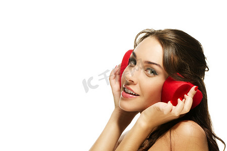 美丽快乐的女人耳朵上拿着红色心形盒子