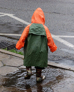 雨中街道摄影照片_男孩在雨中玩耍。