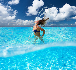 女孩泼水摄影照片_女人用头发在海洋中泼水