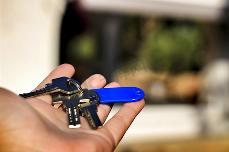 拿钥匙串摄影照片_背景中手拿着一串钥匙和房子