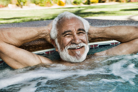 放松在游泳池边缘的愉快的老人