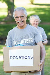 快乐的志愿者老人拿着捐款箱