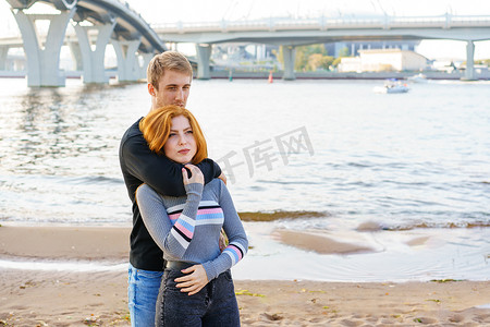 年轻夫妇站在河岸上拥抱