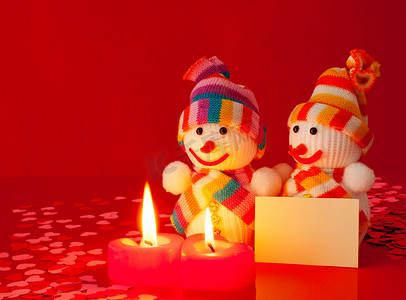 三个雪人和两根燃烧的心形蜡烛