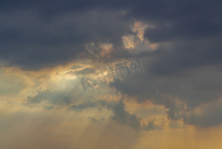 镂空云纹摄影照片_太阳光线穿过云层照耀，在傍晚的天空映衬下形成有趣的光纹。