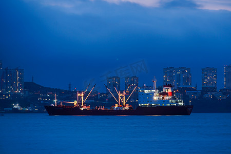 夜景模糊摄影照片_以城市为背景的大海和船只的夜景。