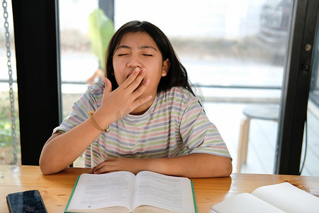 女学生在看书时打哈欠感到疲倦无聊困倦。
