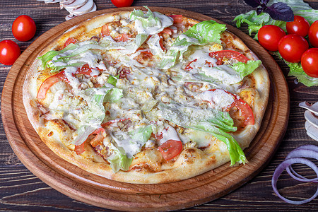 披萨牛排摄影照片_培根和香草披萨，放在木板上，配奶酪和樱桃番茄。