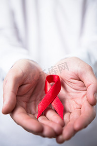艾滋病日摄影照片_拿着红色艾滋病丝带的人