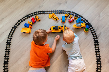 火车玩具摄影照片_学龄前男孩在家里或托儿所玩益智玩具——积木、火车、铁路、车辆。