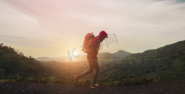 背包的人走在路上摄影照片_年轻男子背着背包走在路上，早上前往雾蒙蒙的山和日出。