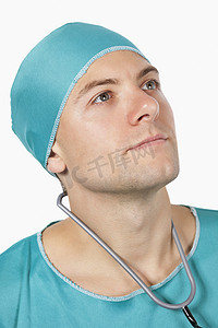 身穿手术服的年轻男性外科医生在白色背景下望向别处